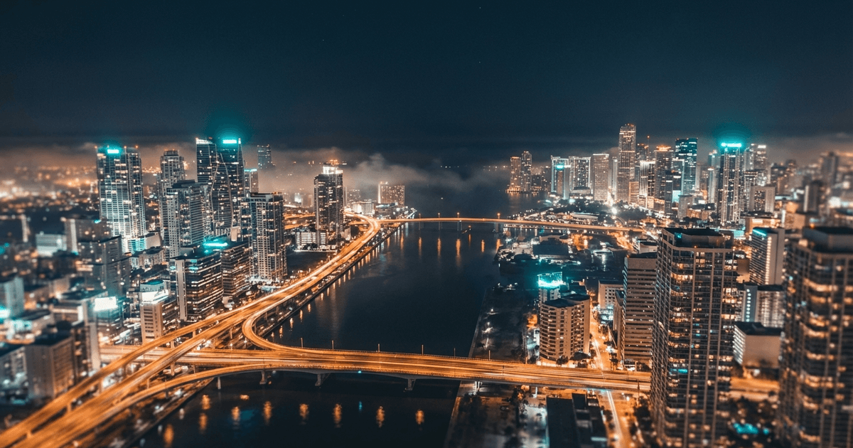 Aerial long-exposure of a coastal city at night with illuminated bridges connecting districts